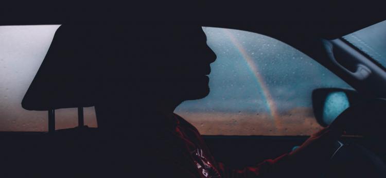 person driving a car with a rainbow in the background