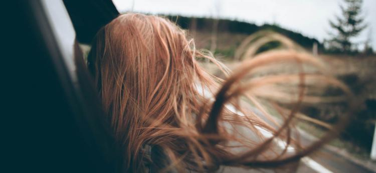 red headed girls hair blowing in the wind leaning out of a car window