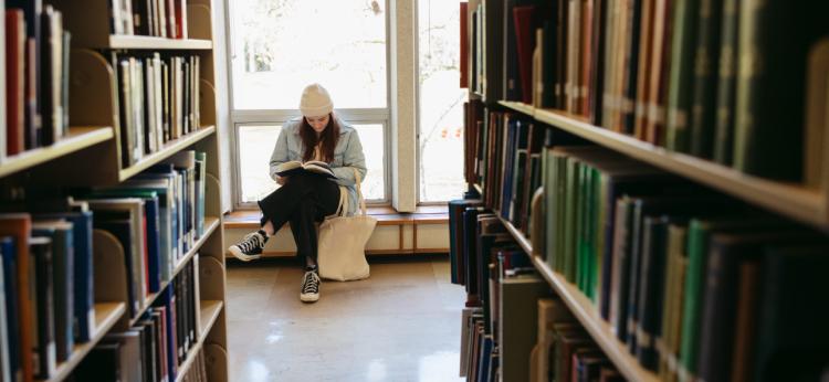 Young Woman Reading In Library At College.