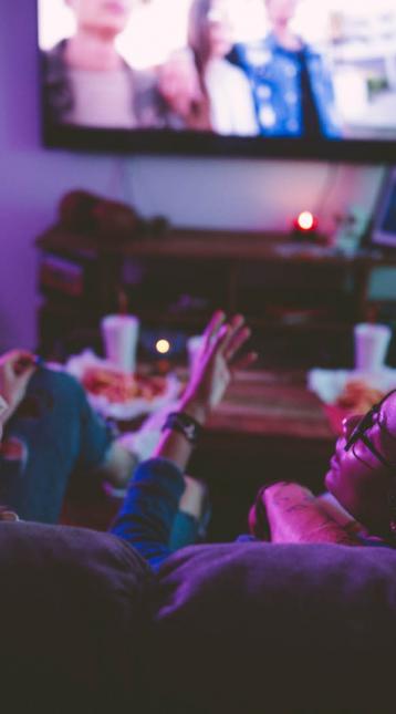 girls in dim light laughing and watching tv