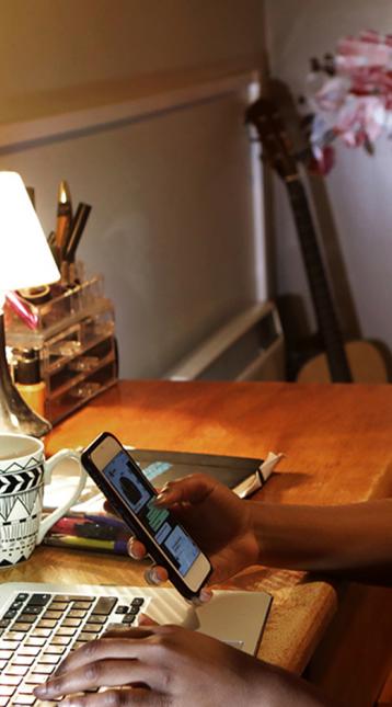 Woman sitting at desk looking at phone and laptop