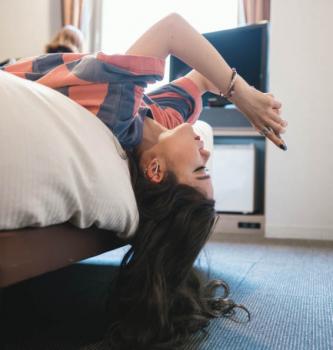 girl lying on bed upside down texting on her phone