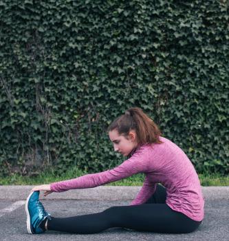 Fifteen year old girl stretches before going on urban run, Seattle, Washington